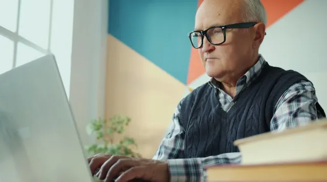 A retired man uses a laptop computer